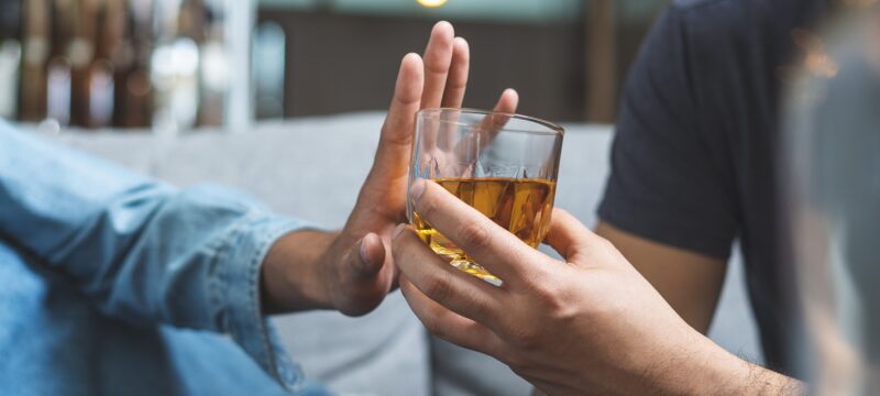 Hand of a person refusing a glass of alcohol offered by another person